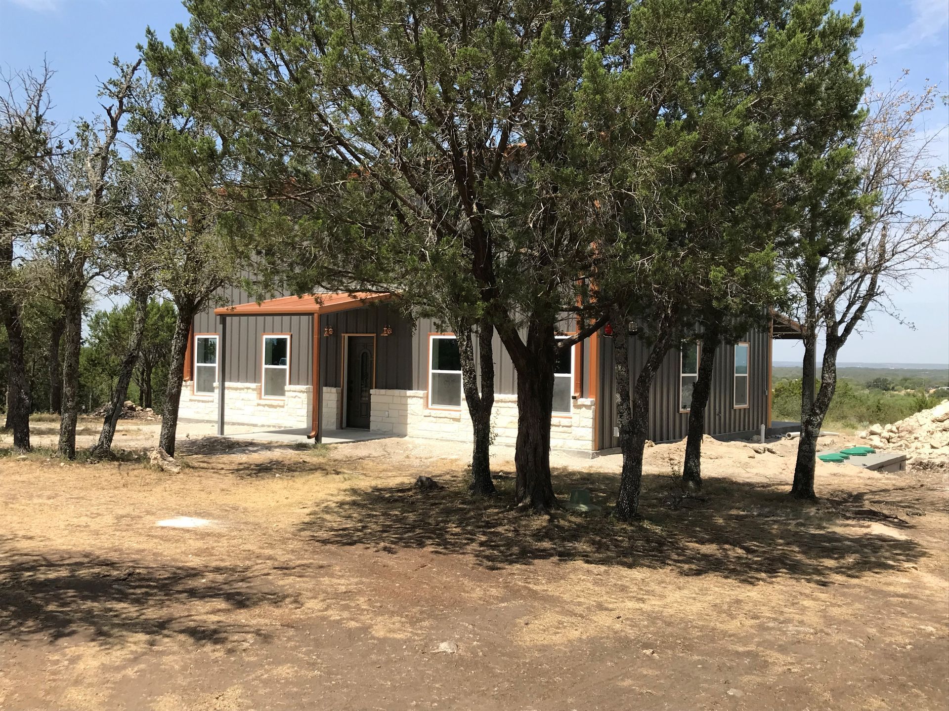 A small house is surrounded by trees in a field.