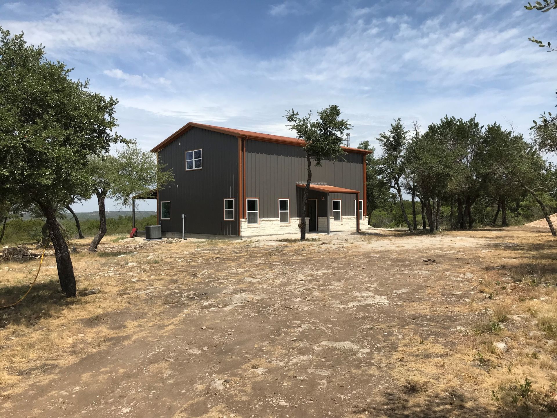 A large house is sitting in the middle of a field surrounded by trees.