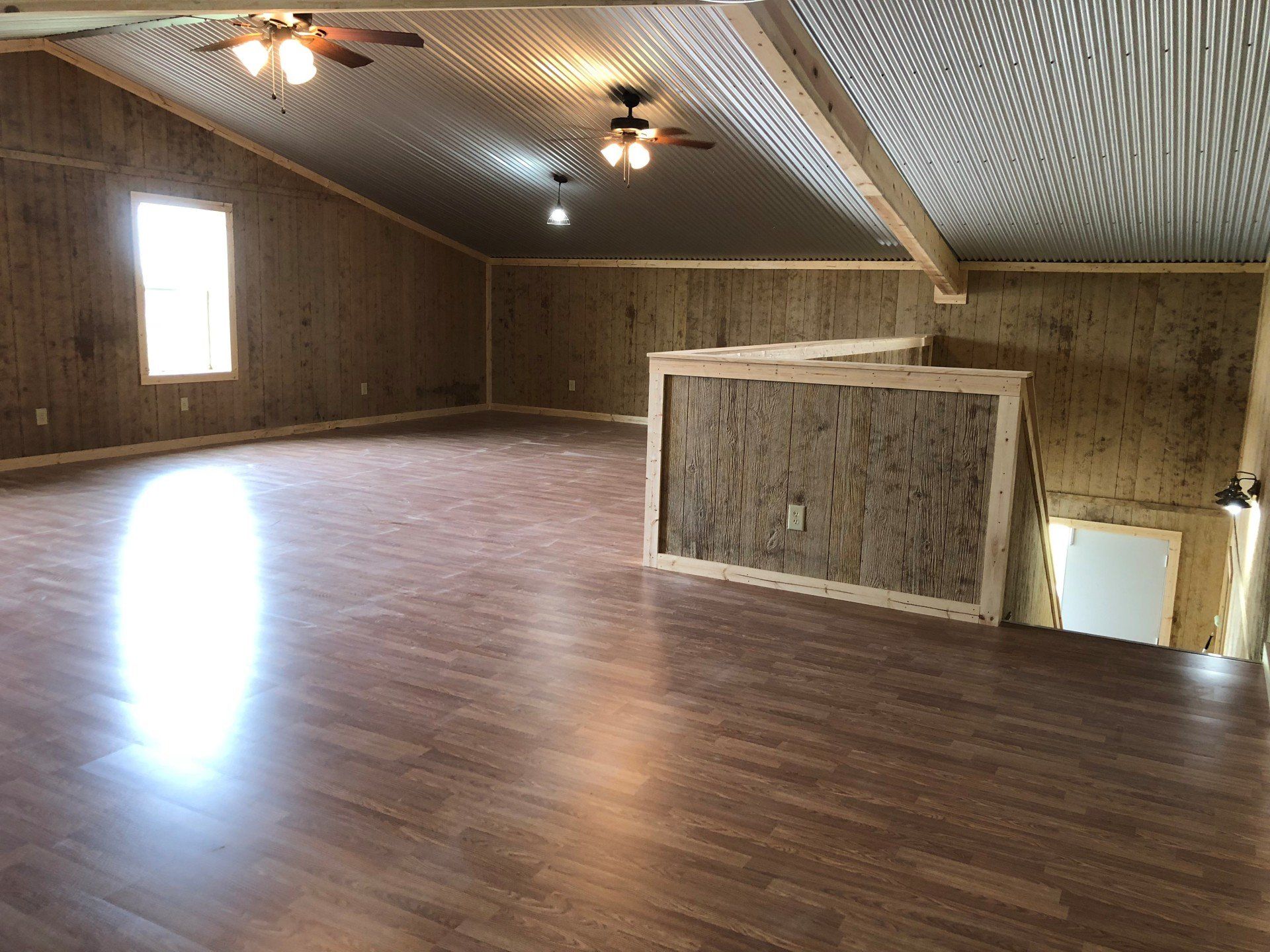 A large empty room with a wooden floor and ceiling fan.