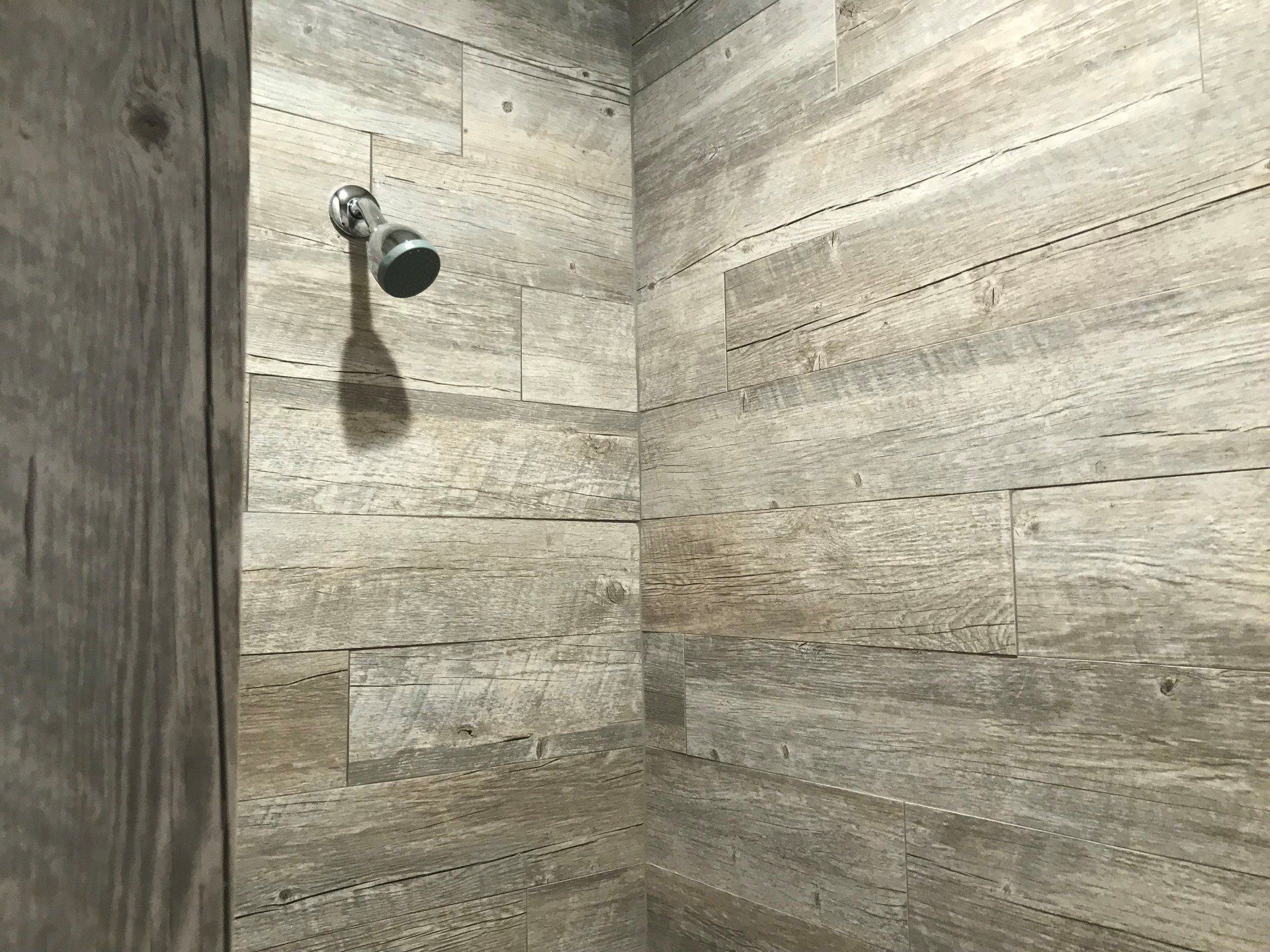 A shower with a wooden wall and a shower head.