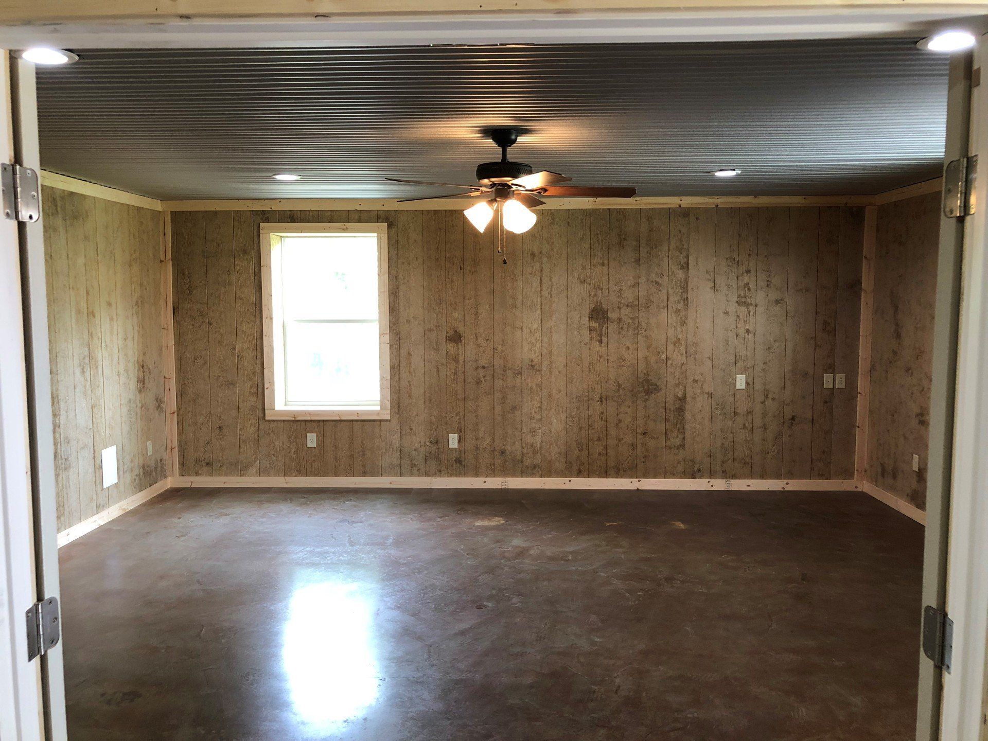 An empty room with a ceiling fan and a window.