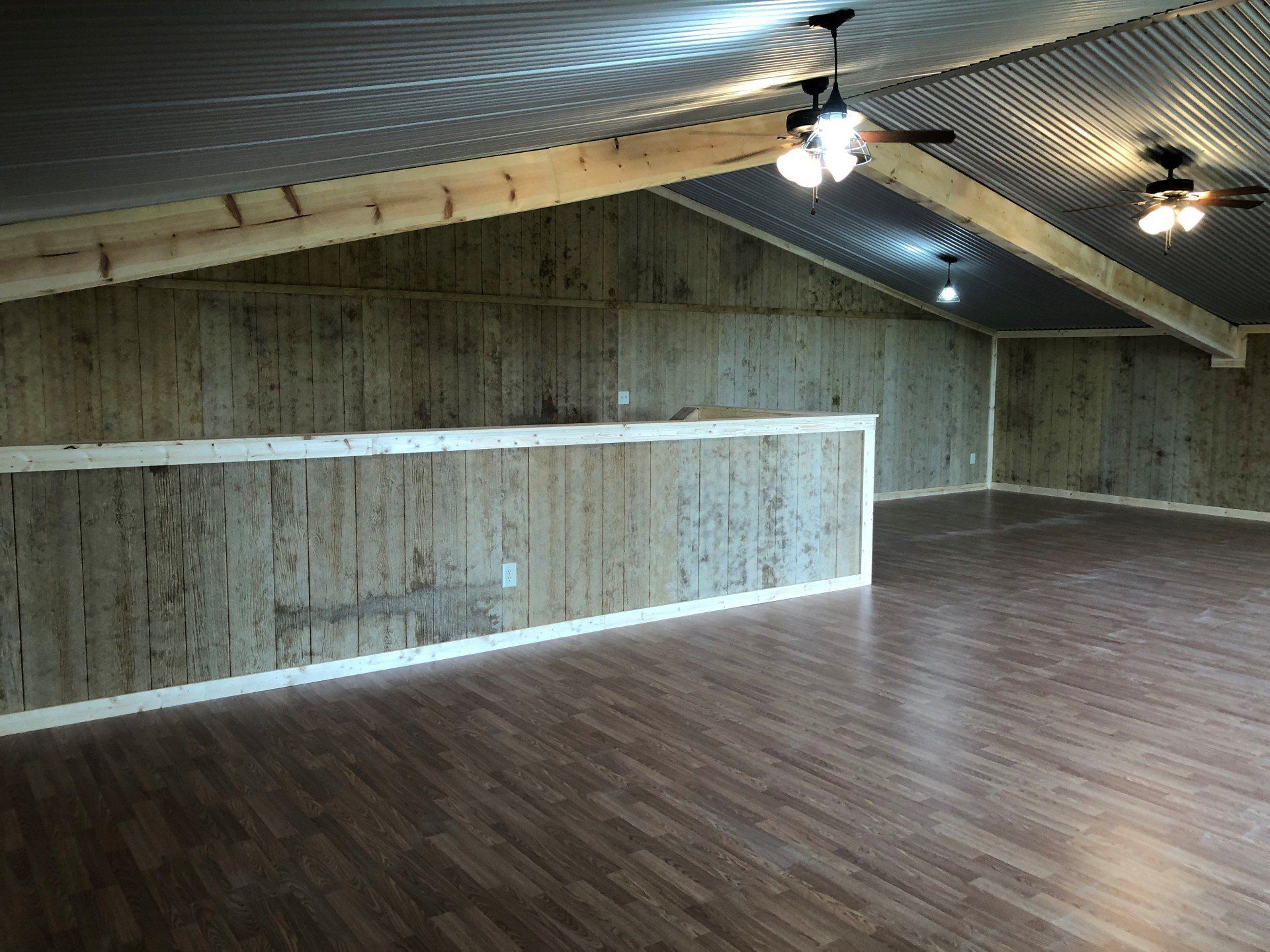 An empty room with wooden walls and a ceiling fan