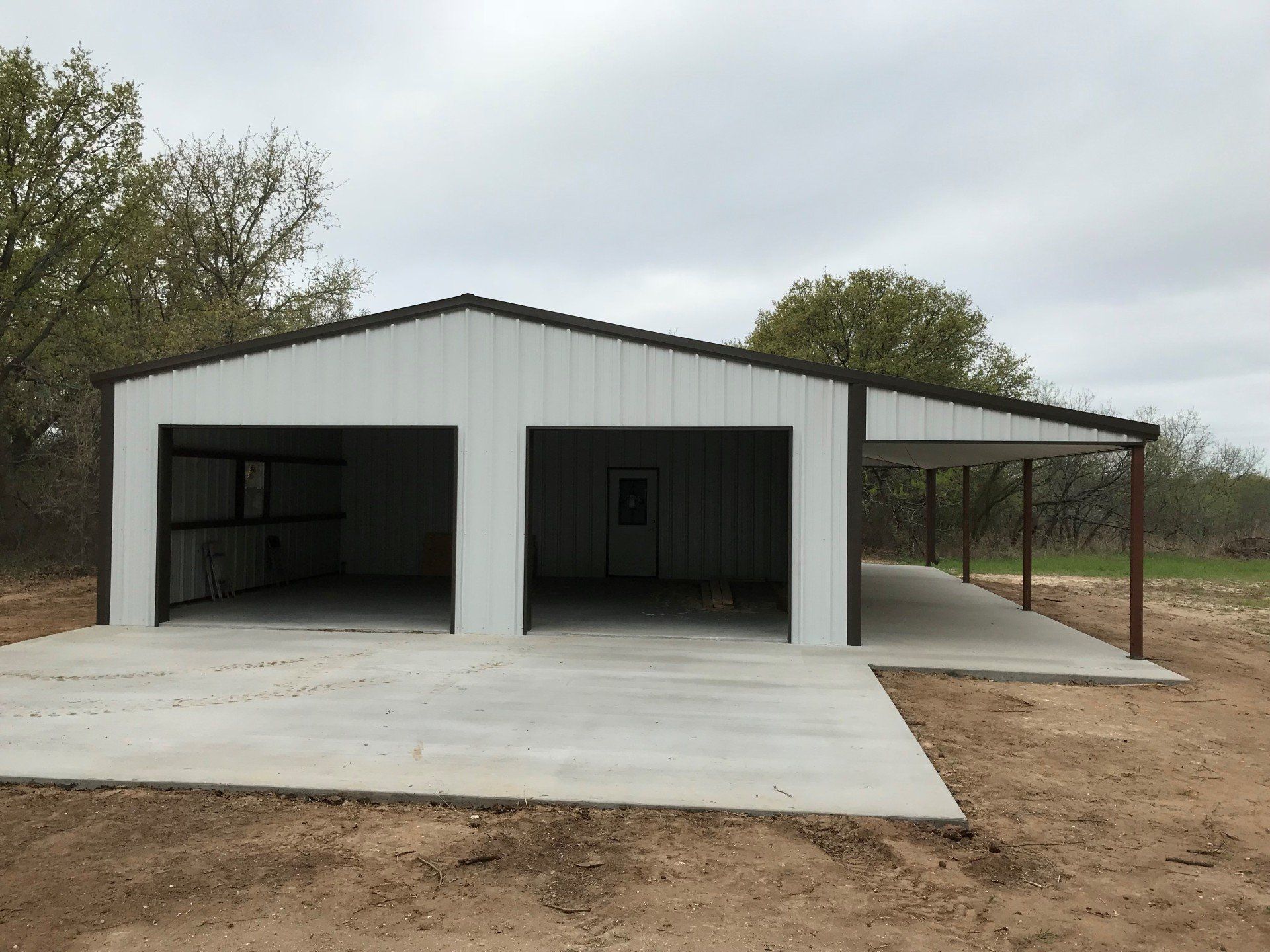 A white garage with a canopy and a concrete driveway.