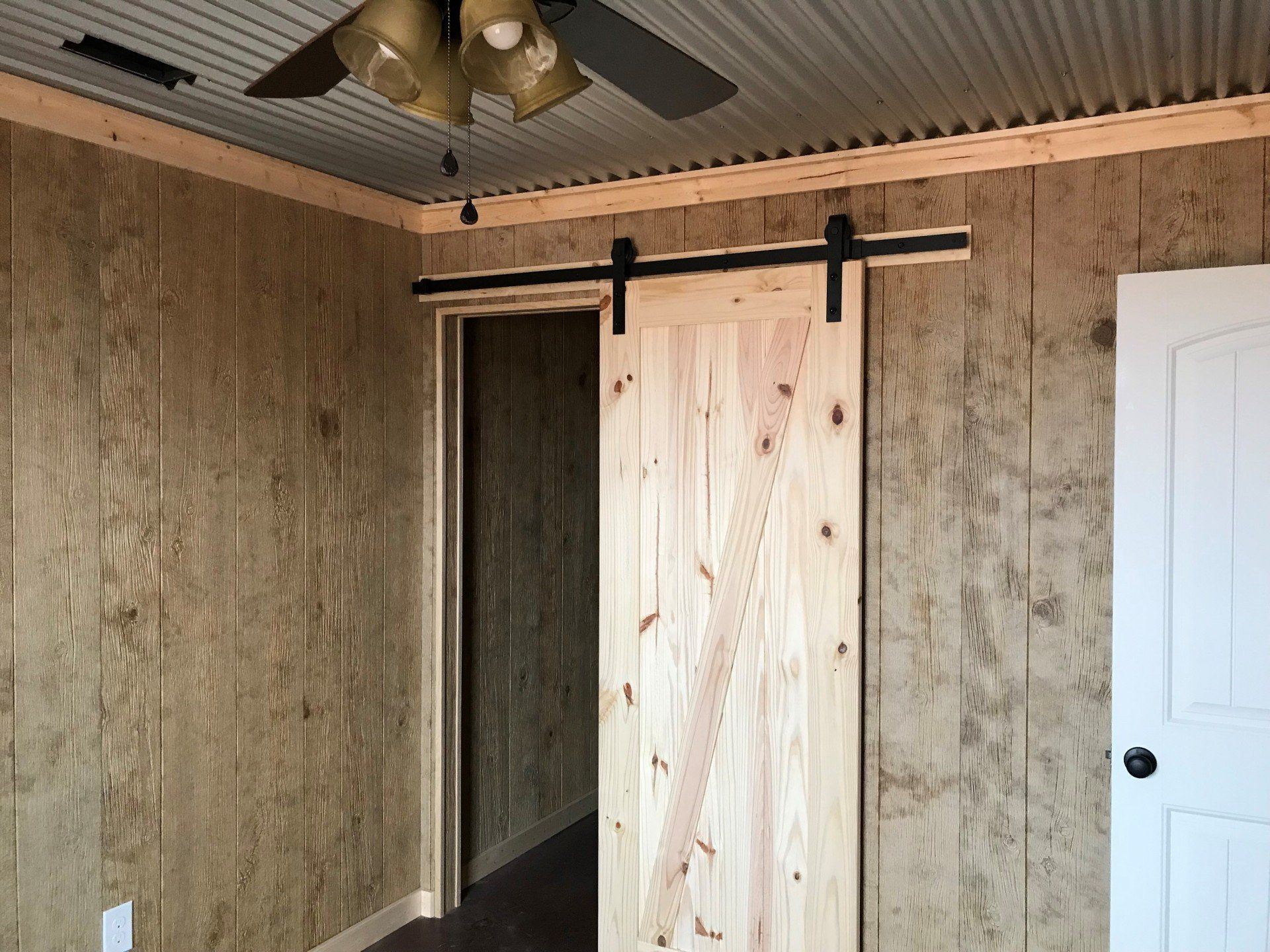 A room with a sliding barn door and a ceiling fan.