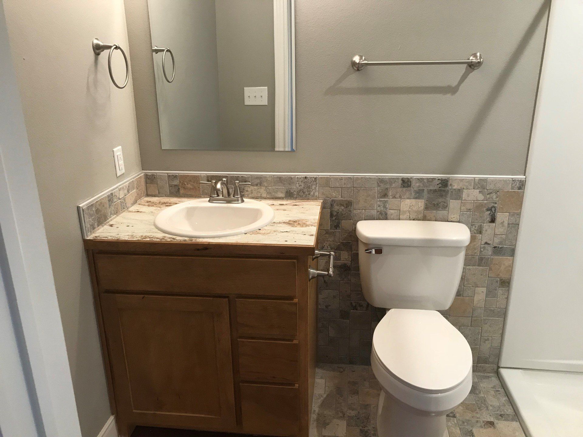 A bathroom with a toilet , sink and mirror.
