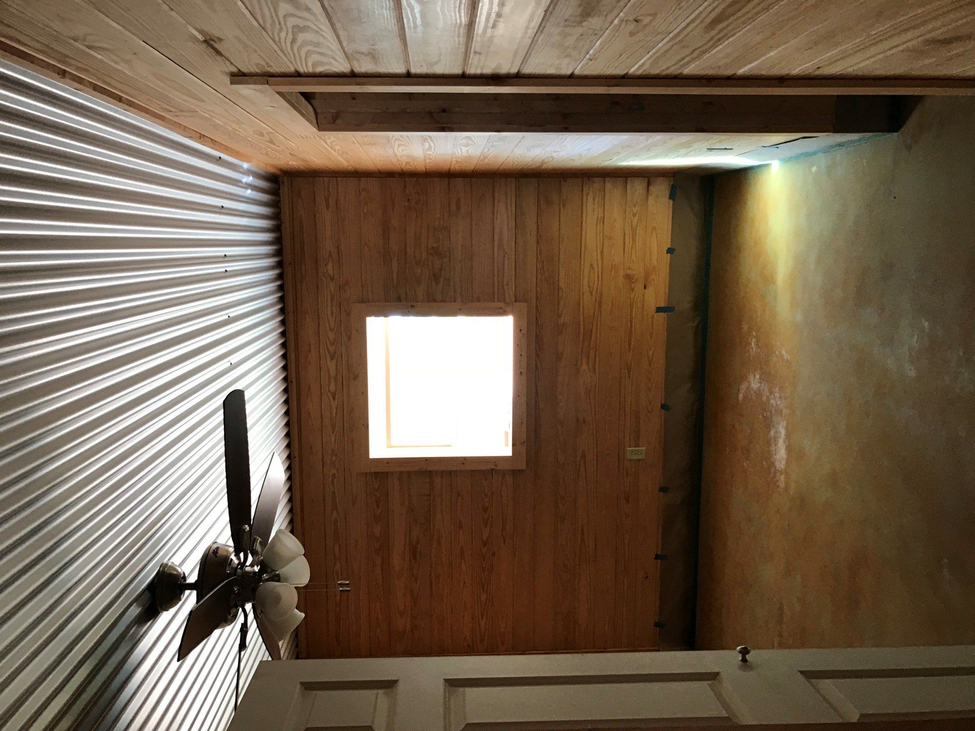 A room with a ceiling fan and a window