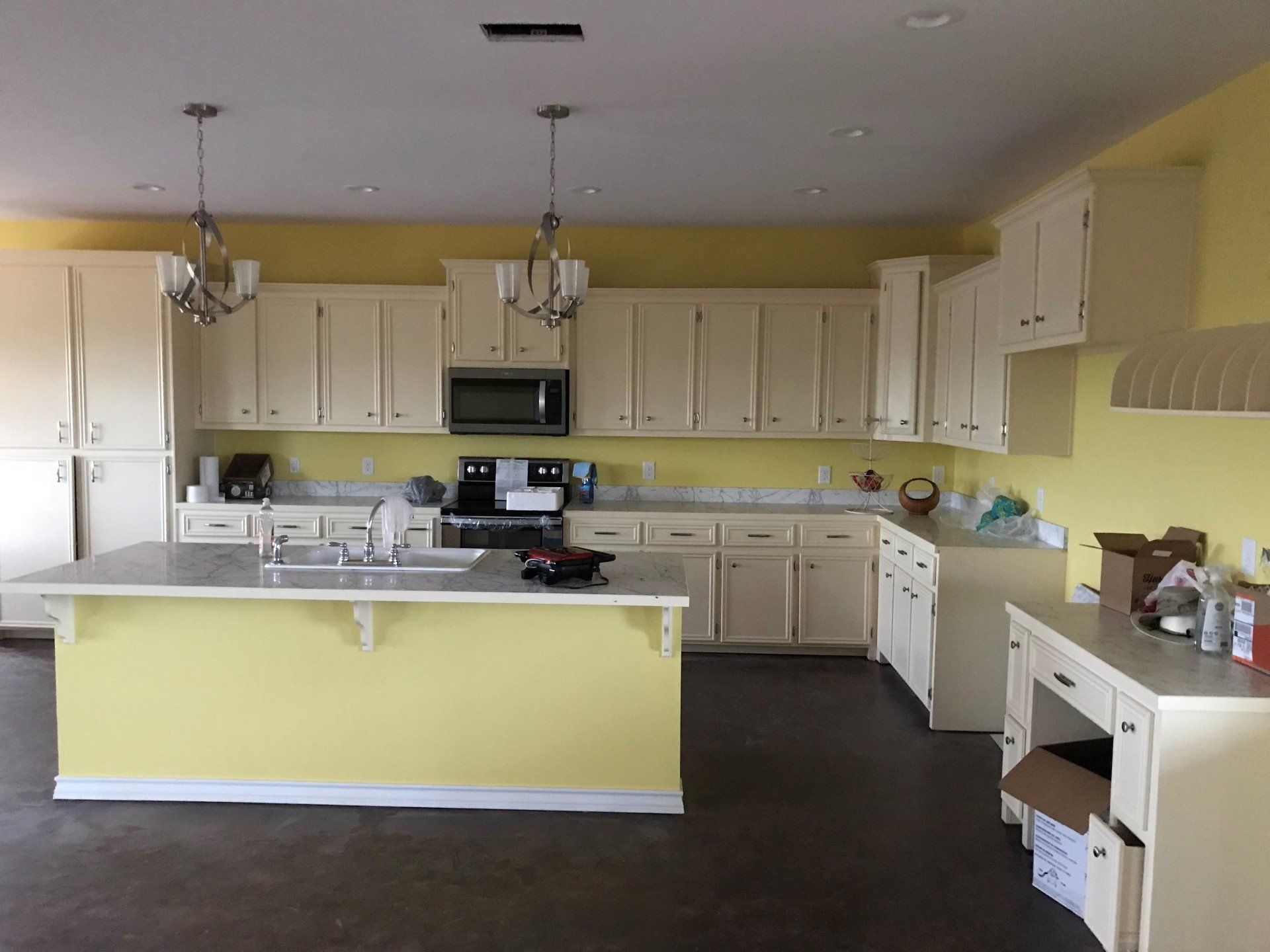A kitchen with yellow walls and white cabinets