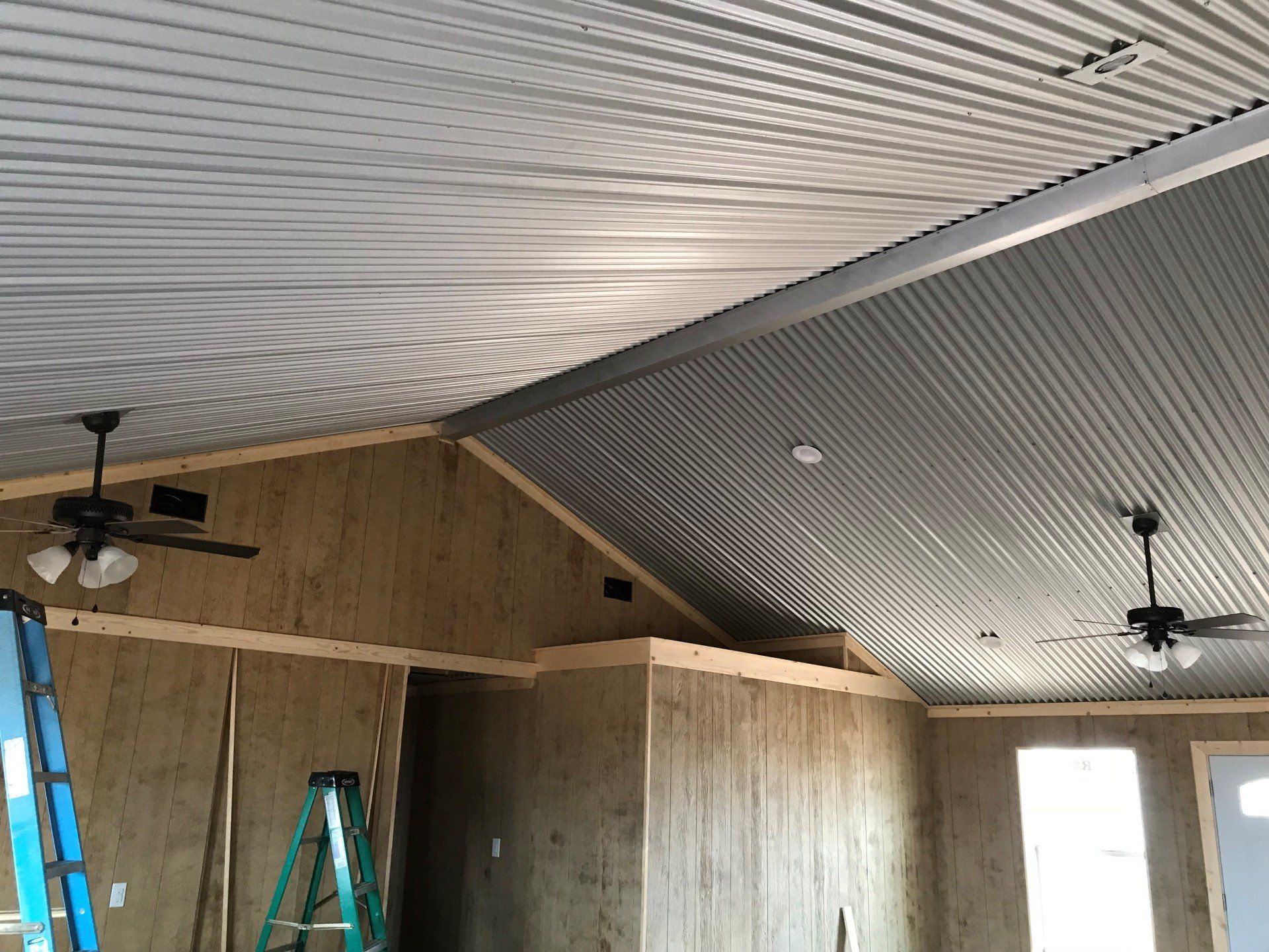 A room with a ceiling fan and a ladder in it.