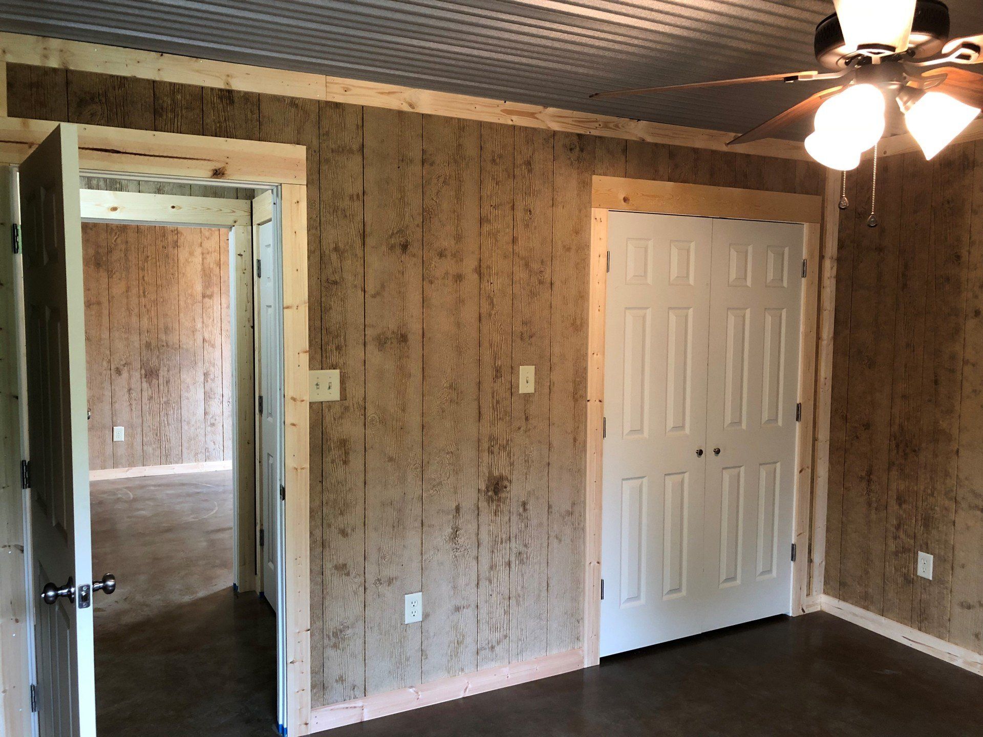 An empty room with a ceiling fan and two doors.