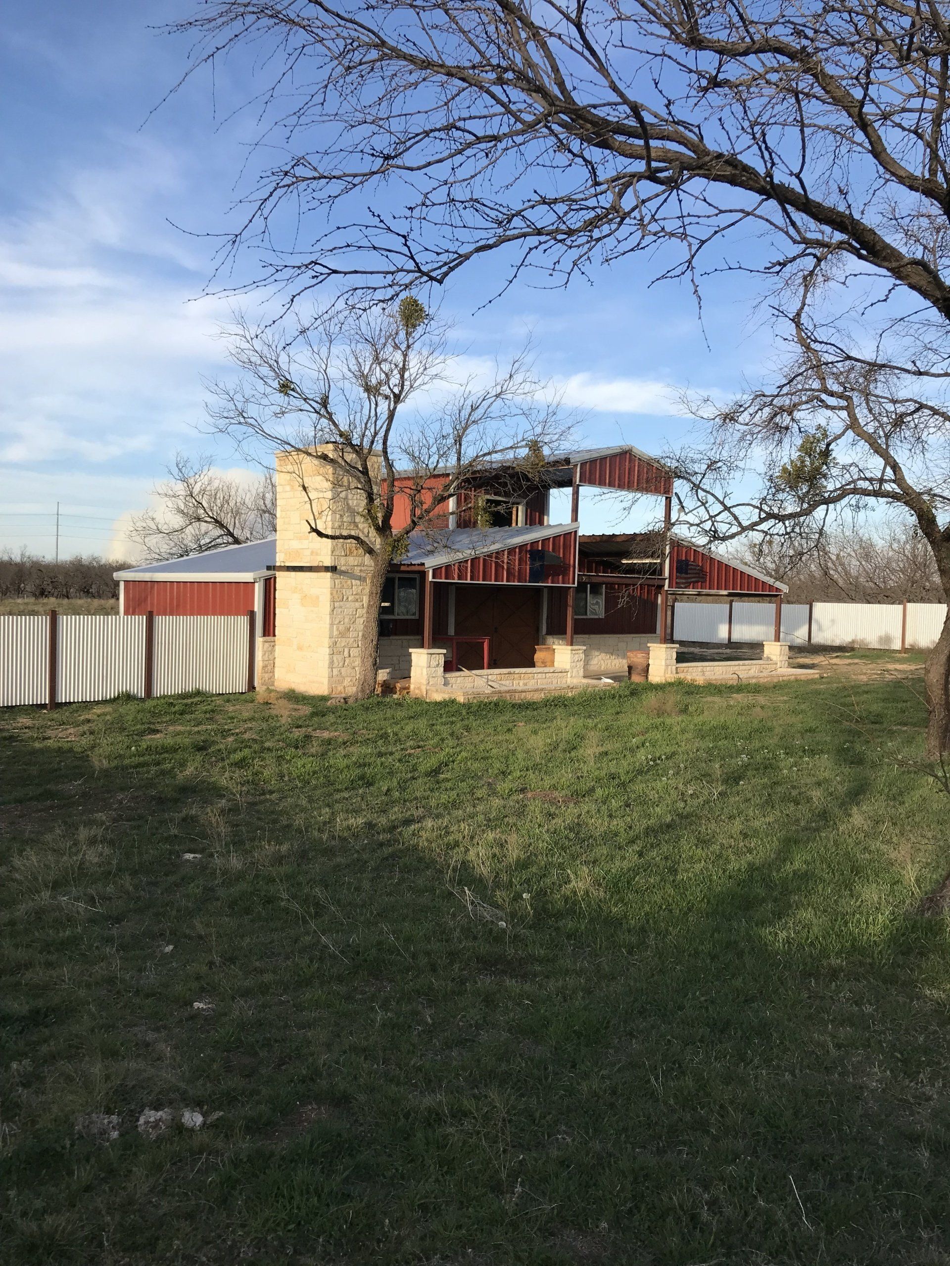 A red barn is sitting in the middle of a grassy field.
