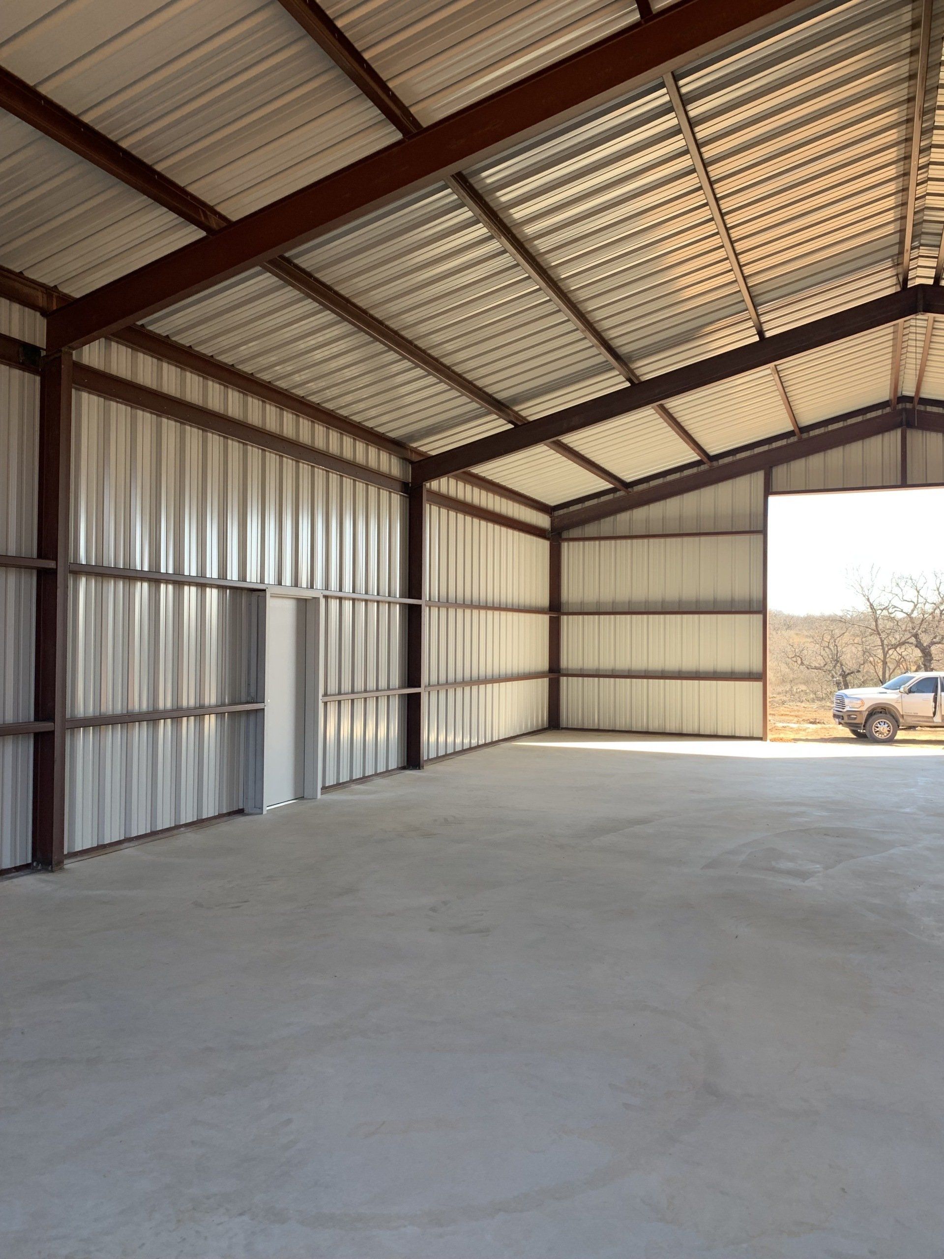 An empty metal building with a truck parked inside of it