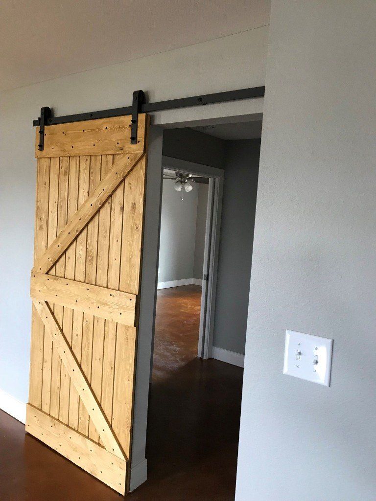 A sliding barn door is open to a hallway in a house.