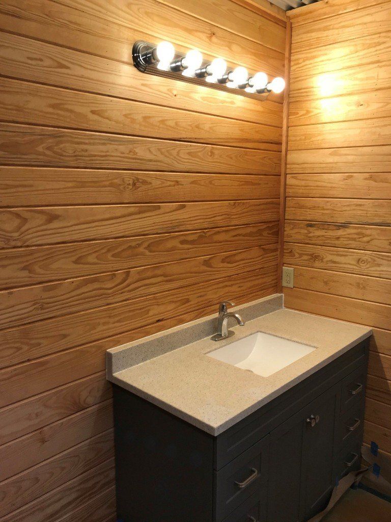 A bathroom with a sink and a wooden wall.