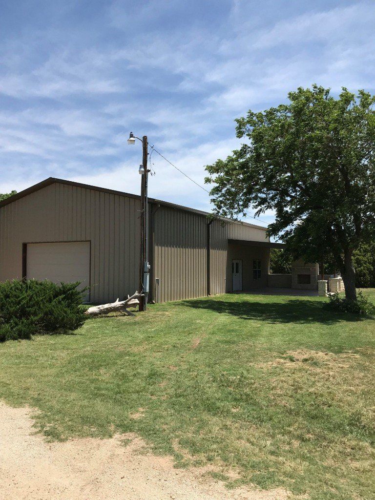 A large metal building is sitting in the middle of a grassy field.