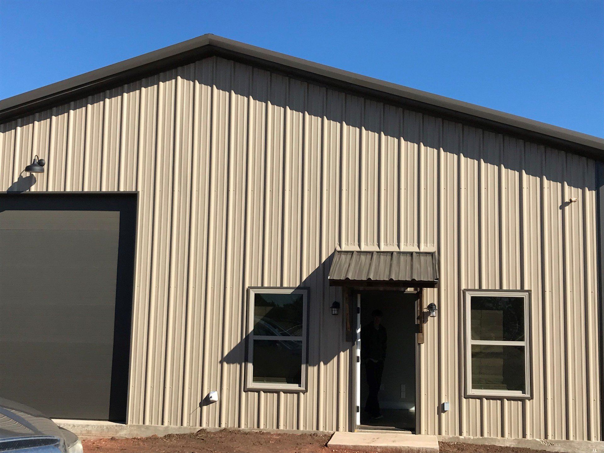 A large metal building with a garage door and windows.