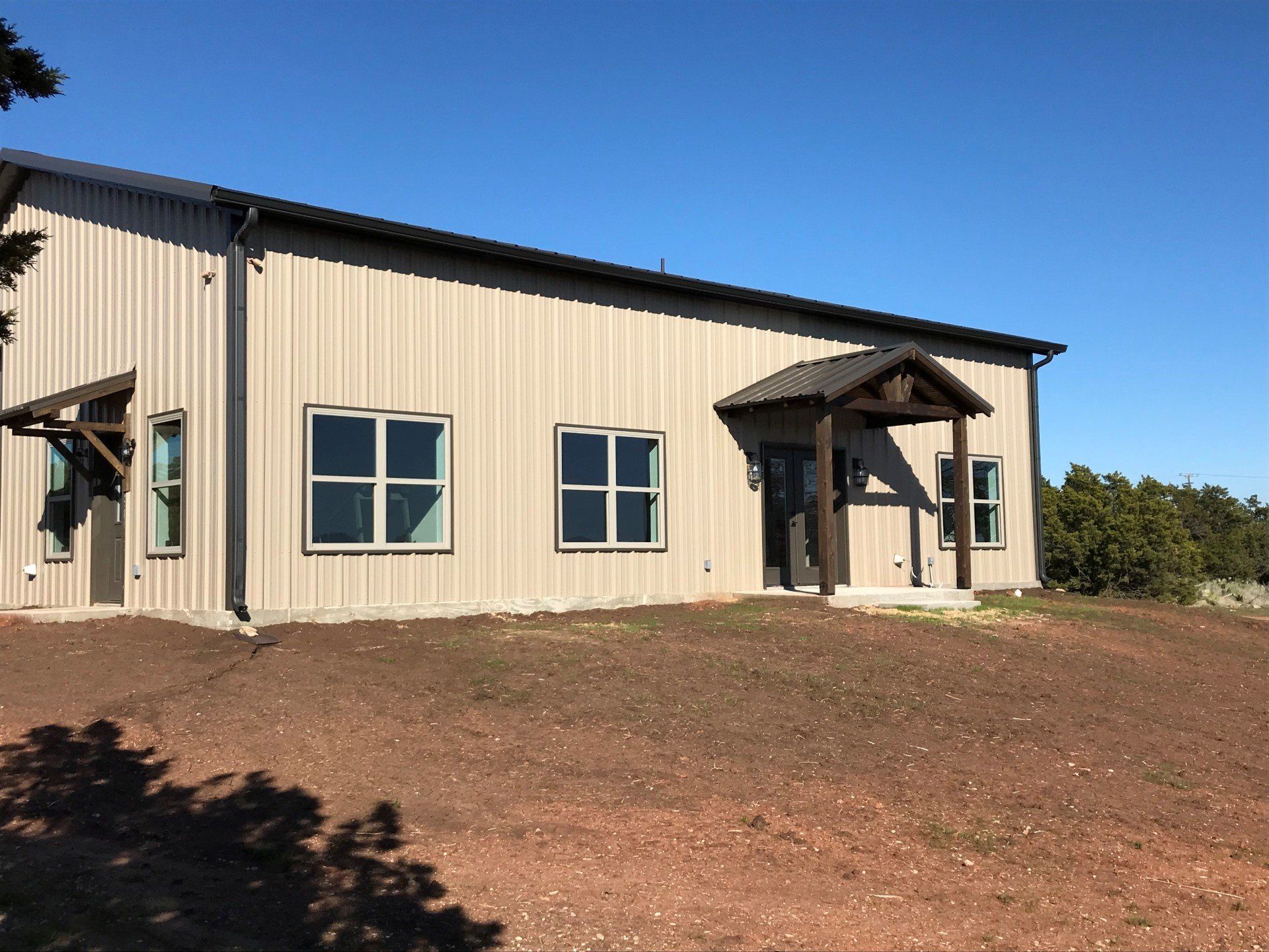 A large building with a lot of windows is sitting on top of a dirt field.