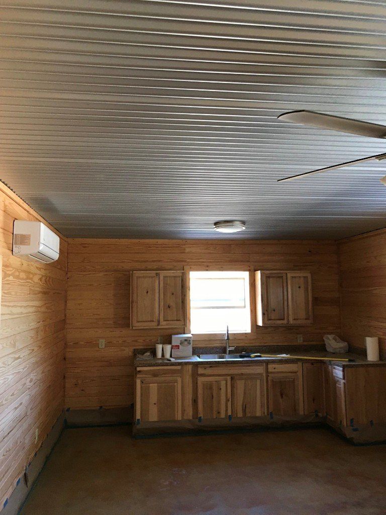 A kitchen with wooden cabinets , a sink , and a ceiling fan.