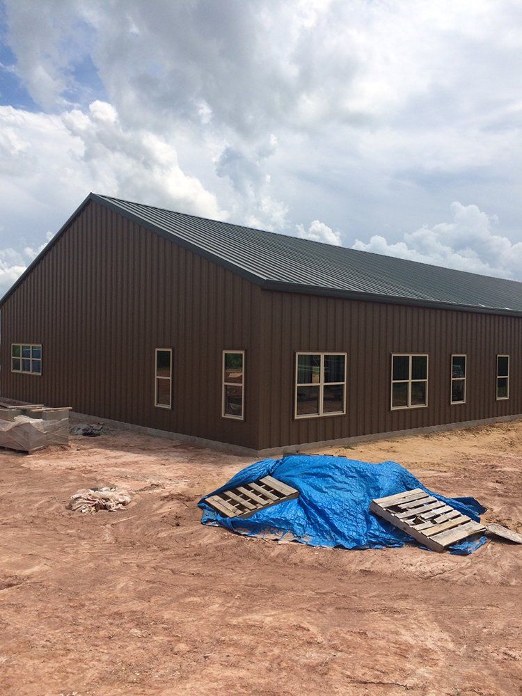 A large brown building is being built in the middle of a dirt field.