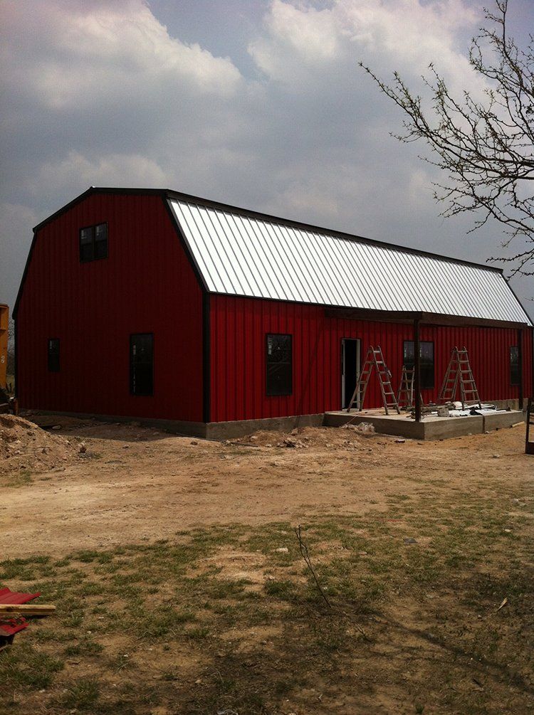 A large red barn with a white roof is under construction