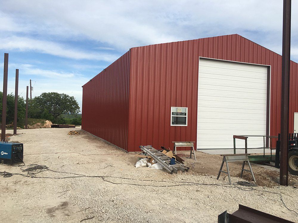 A large red building with a white garage door is being built.