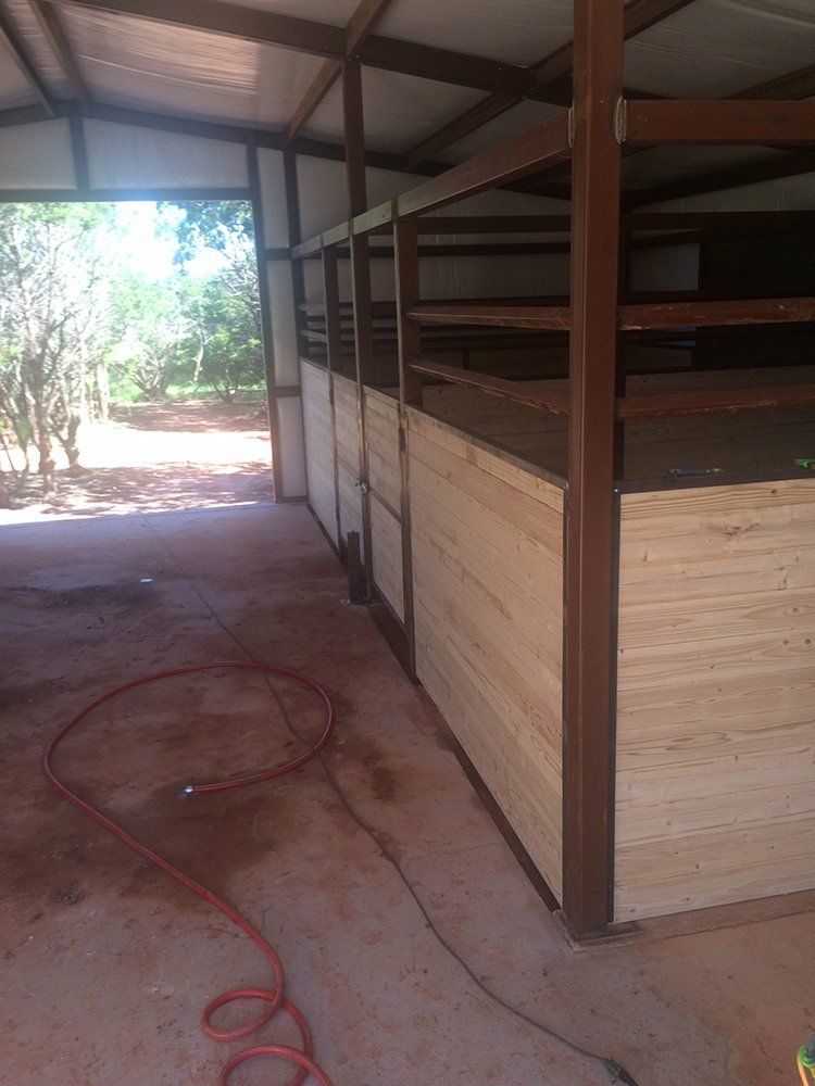 A horse stable with wooden walls and a red hose.
