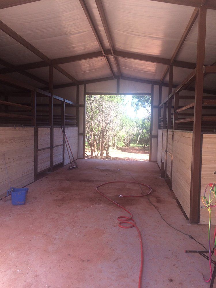 An empty stable with a hose and a bucket in it