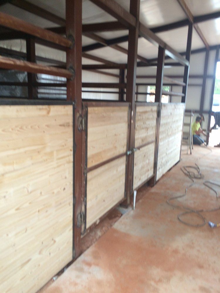 A man in a yellow shirt sits in a stable with wooden walls