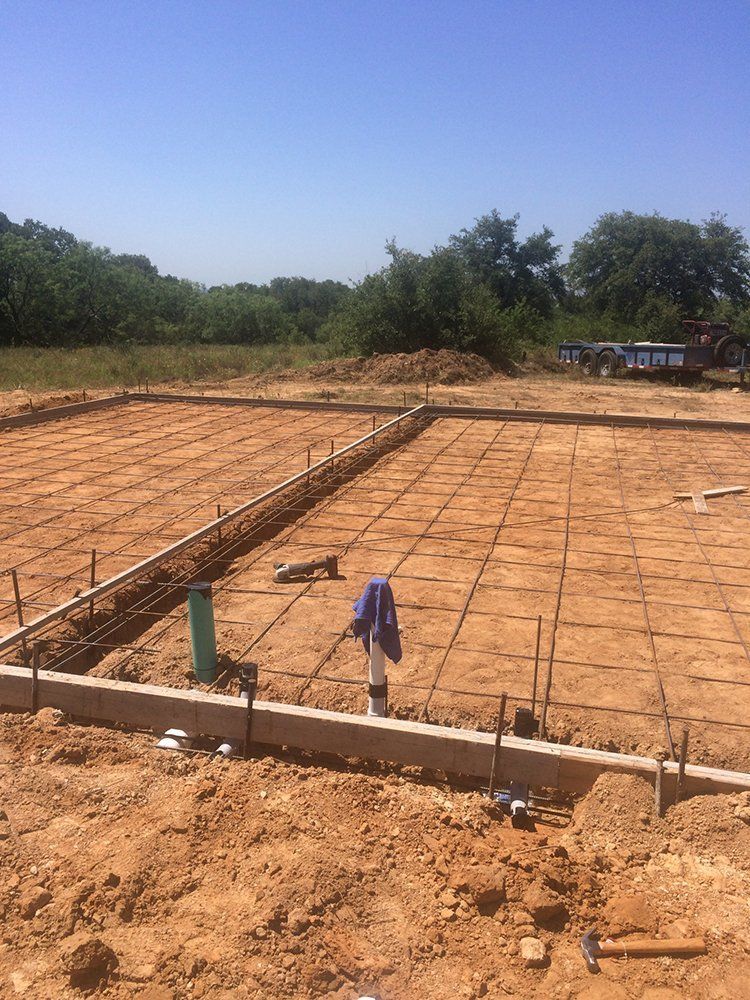 A concrete foundation is being built in a dirt field.