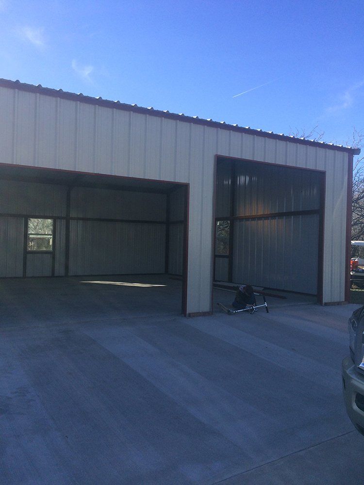 A truck is parked in front of a large metal building.