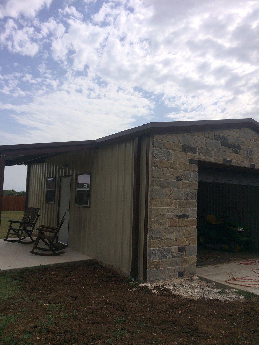 A house with a garage and rocking chairs on the porch.