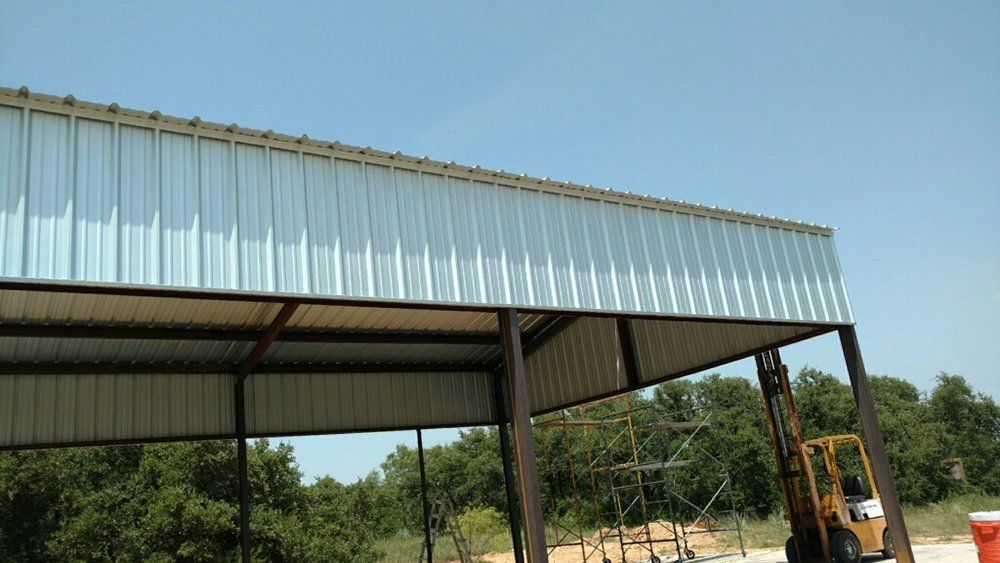 A yellow forklift is parked under a metal roof