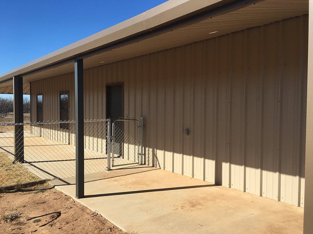 A large metal building with a porch and a gate.
