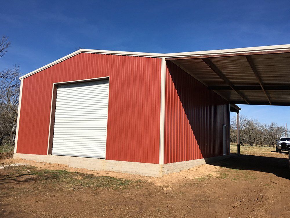 A red building with a white door and a carport underneath it.
