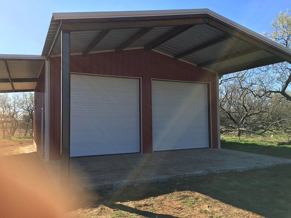 A red garage with two white garage doors and a canopy.