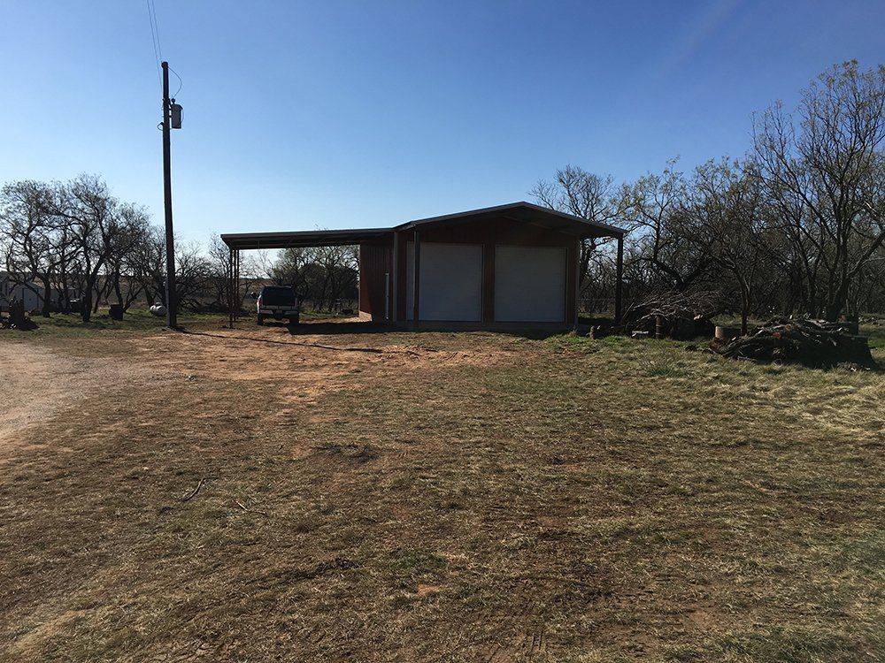 A garage is sitting in the middle of a grassy field.
