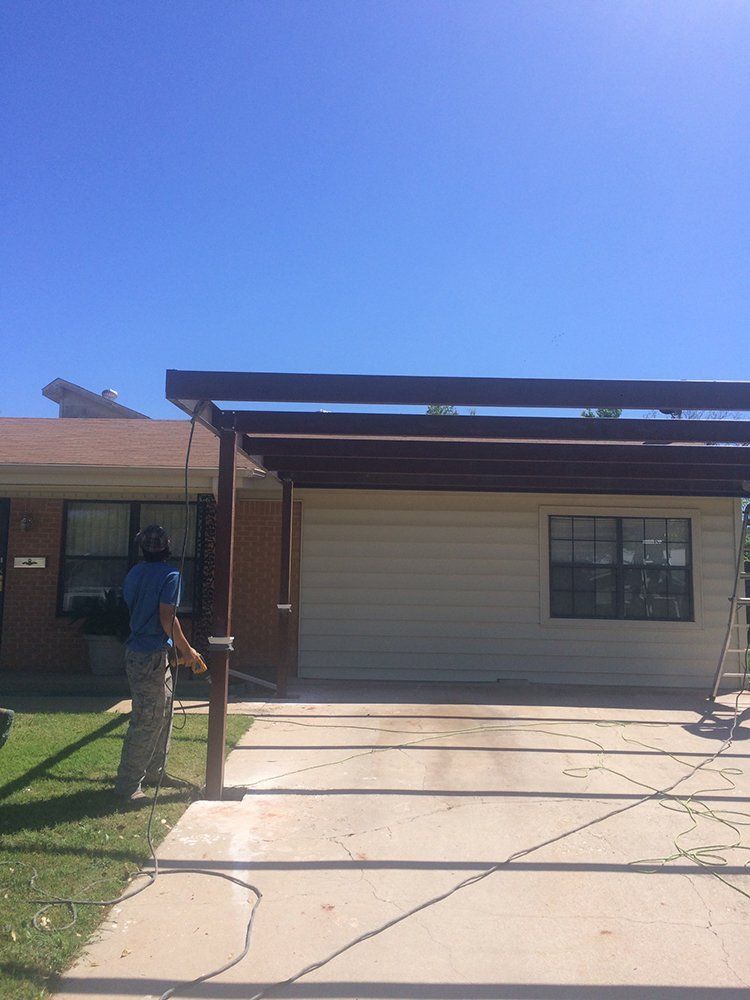 A man is standing in front of a house with a pergola.