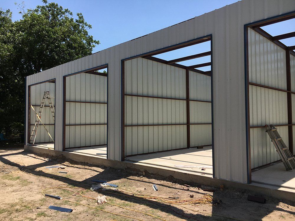 A metal building is being built with a ladder in the background.