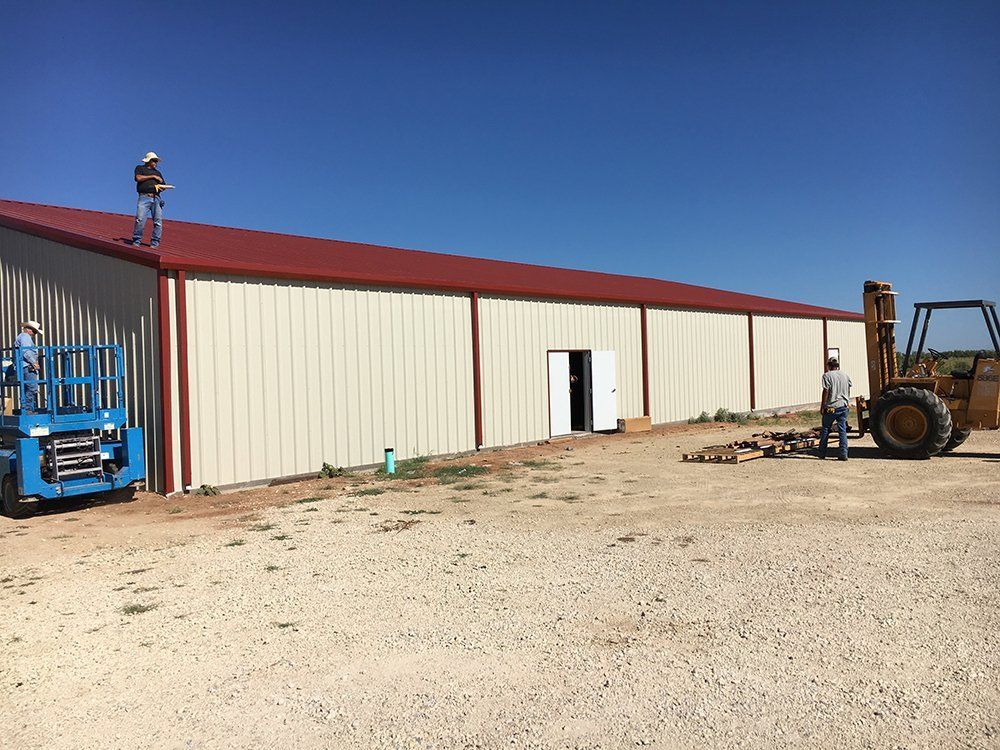 A man is standing on the roof of a building next to a forklift.