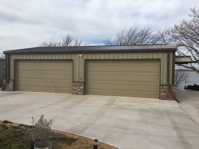 A garage with three garage doors and a driveway next to a body of water.
