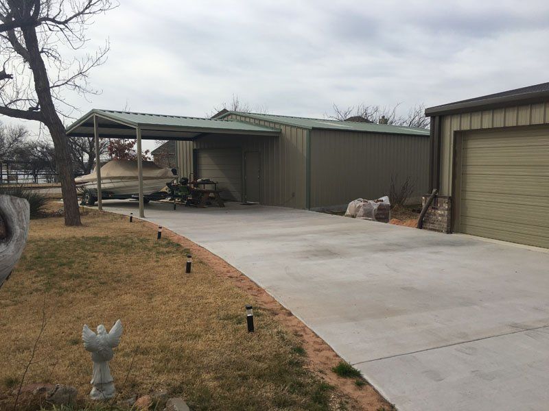 A concrete driveway leading to a garage with a canopy over it.