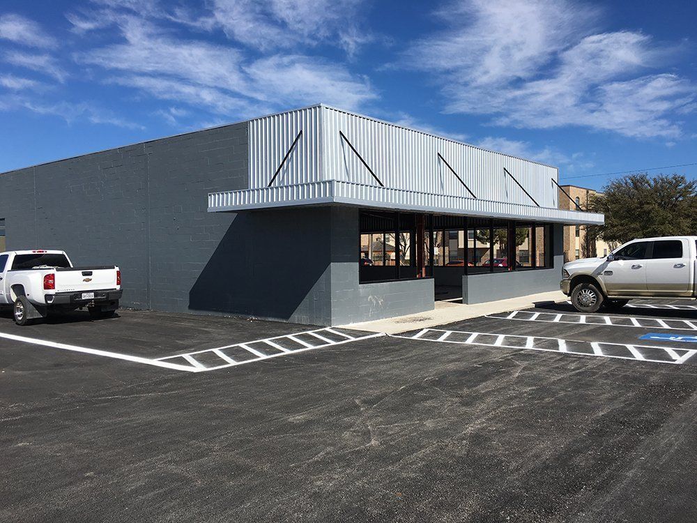 Two white trucks are parked in front of a building.