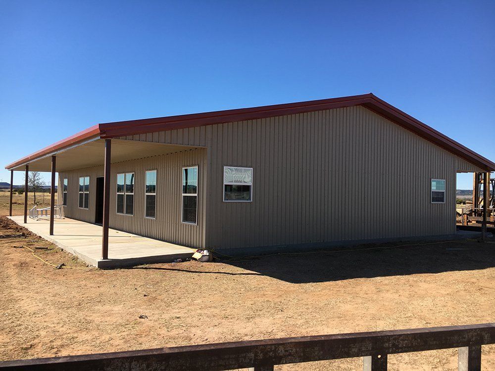 A large metal building with a porch and a lot of windows