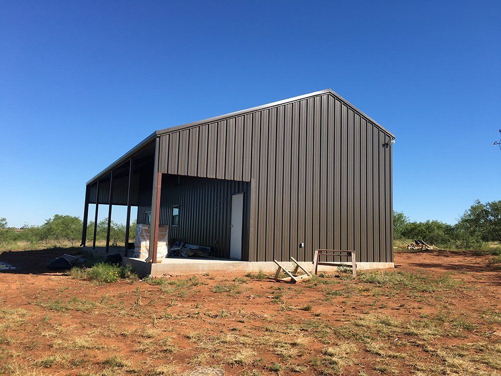 A large metal building is sitting in the middle of a field.