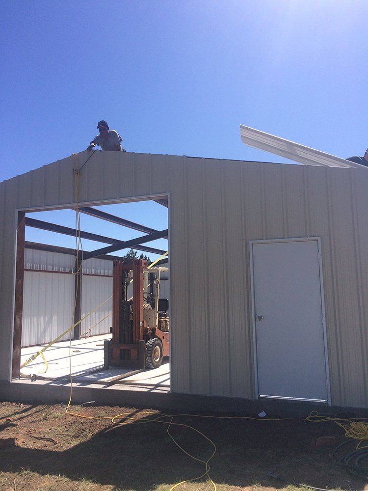 A man is standing on top of a building with a forklift in front of it.