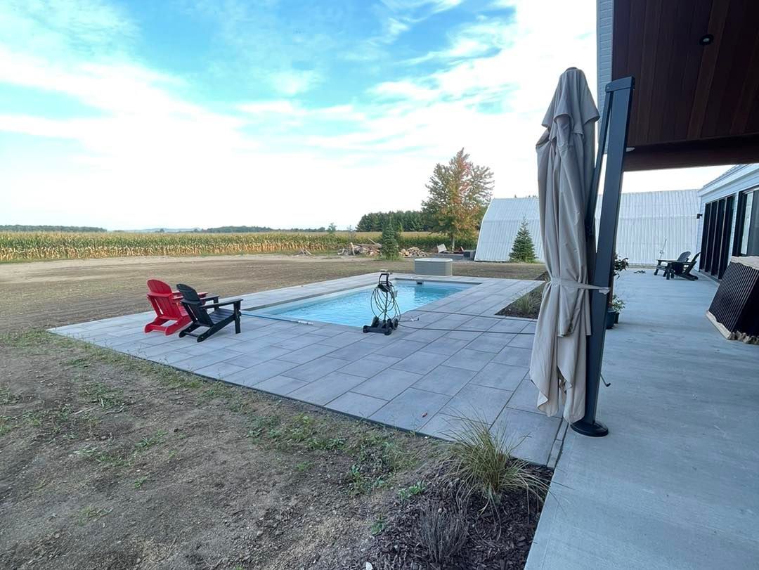 Un patio avec chaises et parasols à côté d'une piscine.