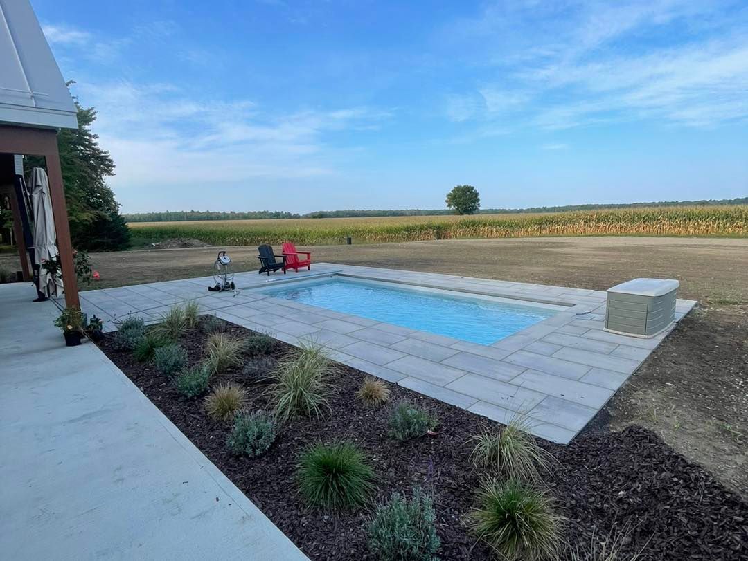 Il y a une grande piscine au milieu d'un champ.