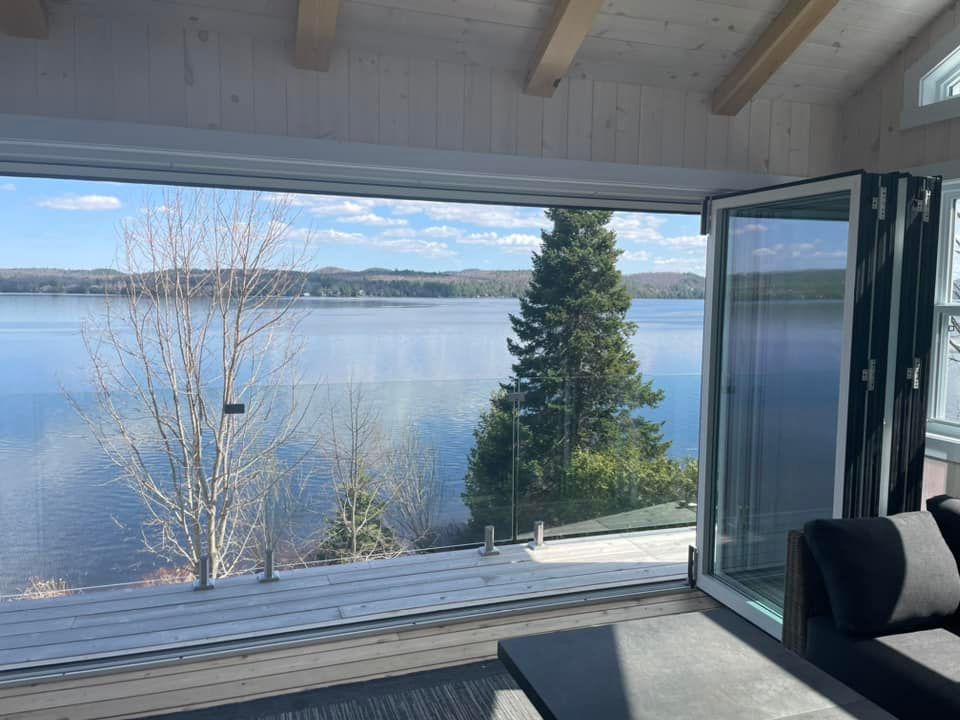 Un salon avec vue sur un lac à travers une grande fenêtre.