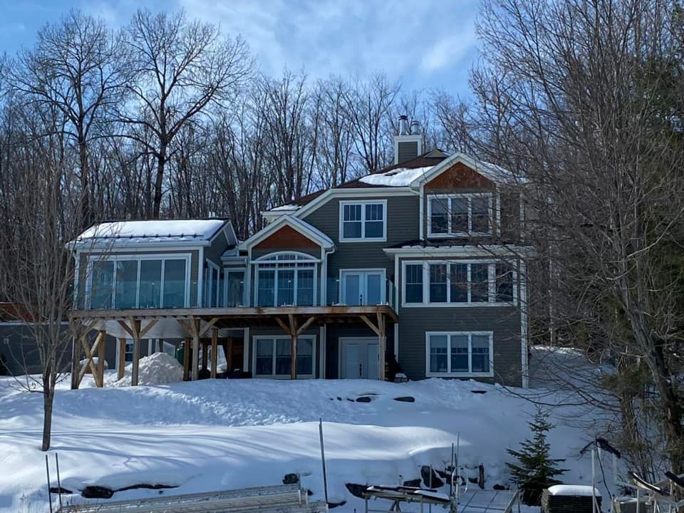 Une grande maison est entourée de neige et d'arbres