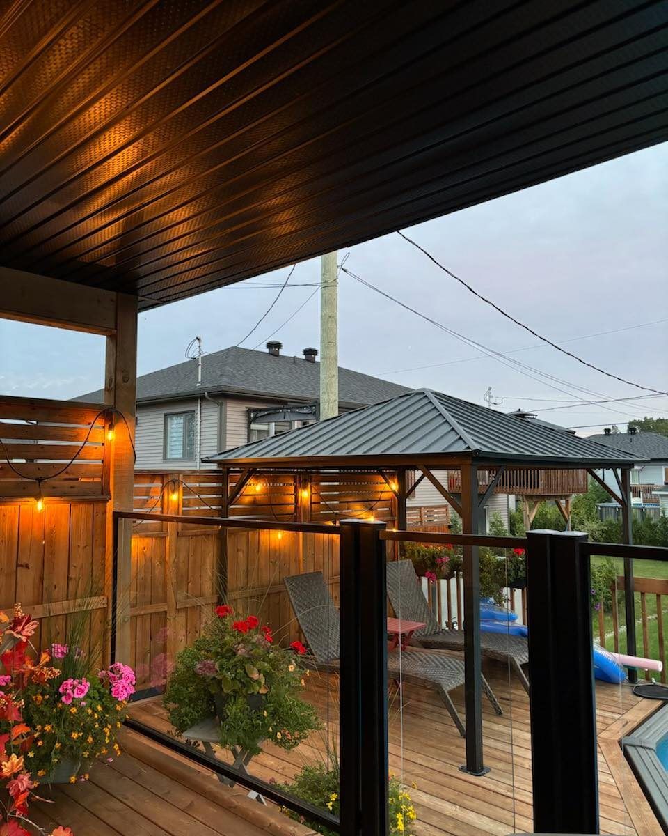 Une terrasse avec un gazebo et une piscine en arrière-plan.