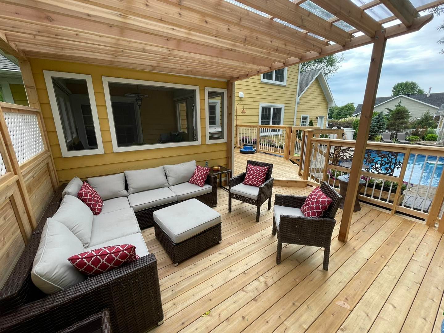 Une terrasse en bois avec un canapé et des chaises sous une pergola.